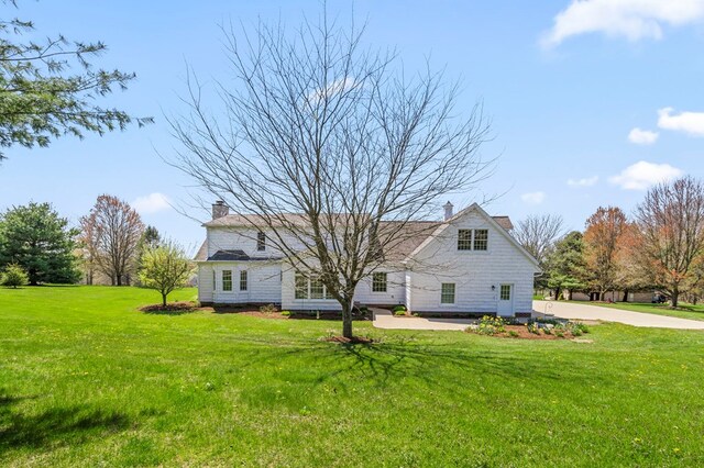 rear view of house featuring a yard and a chimney
