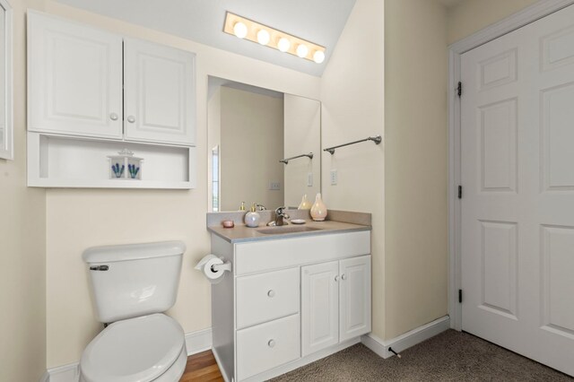 bathroom with baseboards, toilet, and vanity