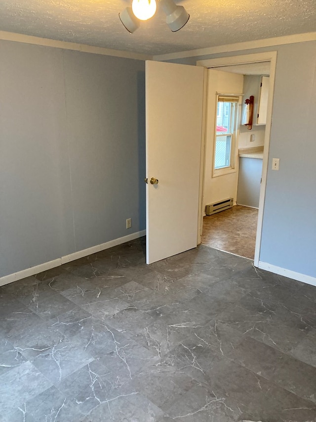 spare room with a baseboard heating unit and a textured ceiling