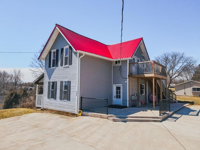 exterior space featuring a deck, a patio, metal roof, and stairs