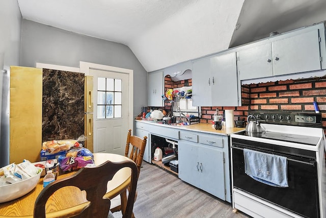 kitchen with lofted ceiling, light countertops, range with electric stovetop, and light wood-type flooring