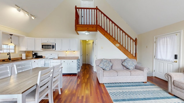 living room with dark wood-style flooring, stairway, high vaulted ceiling, and track lighting