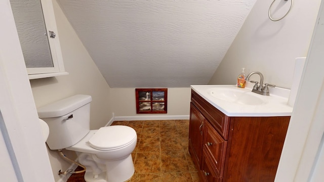 bathroom with baseboards, toilet, lofted ceiling, a textured ceiling, and vanity