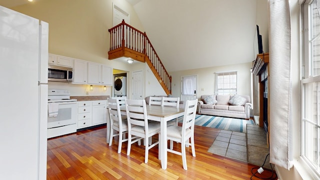 dining room with stairway, stacked washer / dryer, a towering ceiling, and hardwood / wood-style flooring