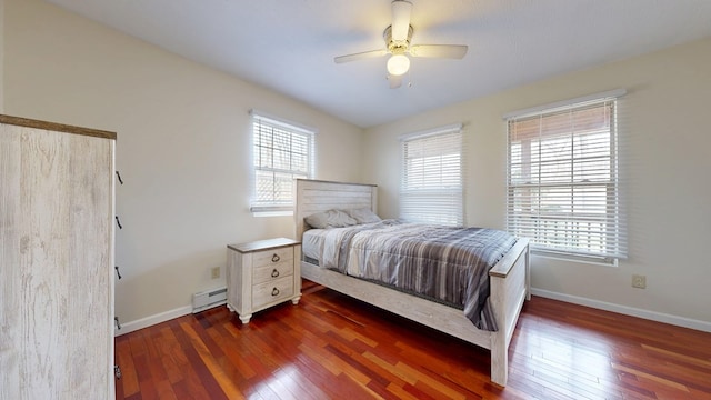 bedroom with baseboards, multiple windows, baseboard heating, and hardwood / wood-style flooring