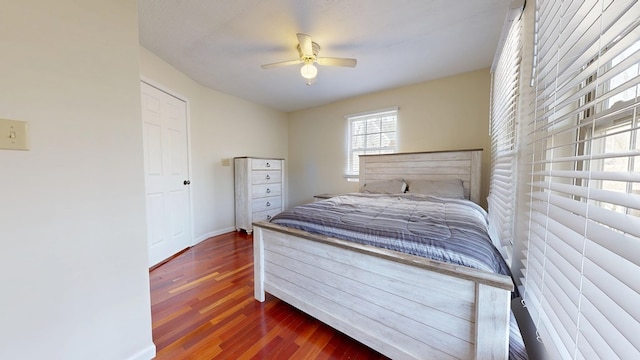 bedroom with ceiling fan, wood finished floors, and baseboards