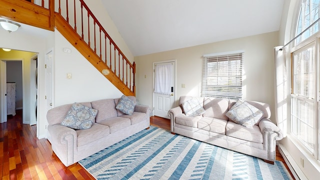 living room featuring stairs, a baseboard heating unit, plenty of natural light, and wood finished floors