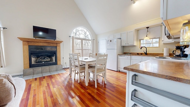 kitchen with light wood-type flooring, white appliances, white cabinetry, and plenty of natural light