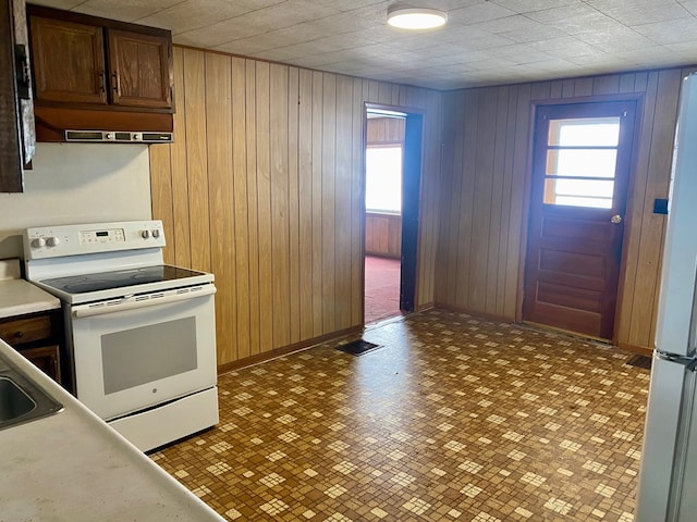 kitchen featuring white appliances, extractor fan, and wood walls