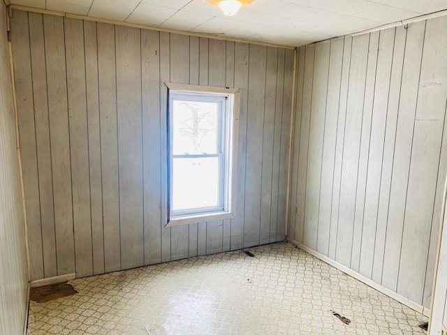 unfurnished room featuring plenty of natural light and wood walls