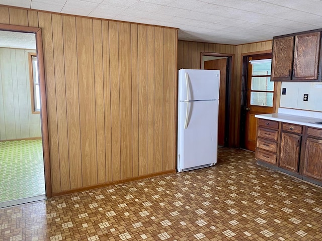 kitchen with white refrigerator and wooden walls