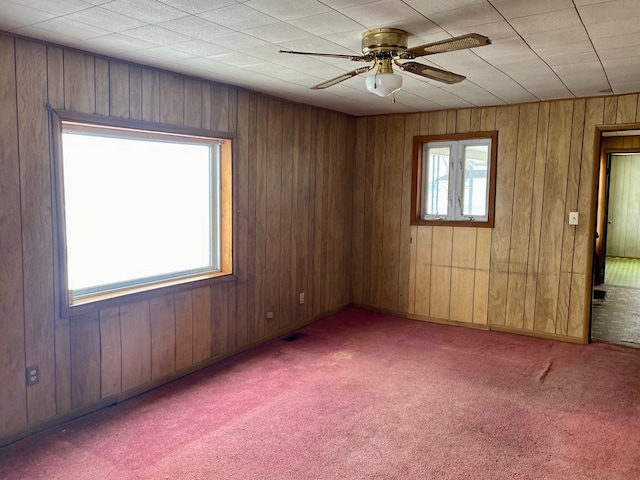 empty room featuring ceiling fan, carpet floors, and wood walls