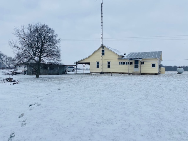 snow covered back of property with solar panels