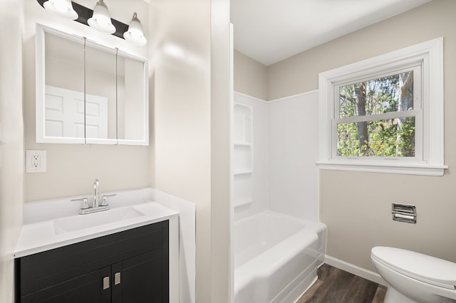 bathroom featuring vanity, toilet, baseboards, shower / washtub combination, and wood finished floors