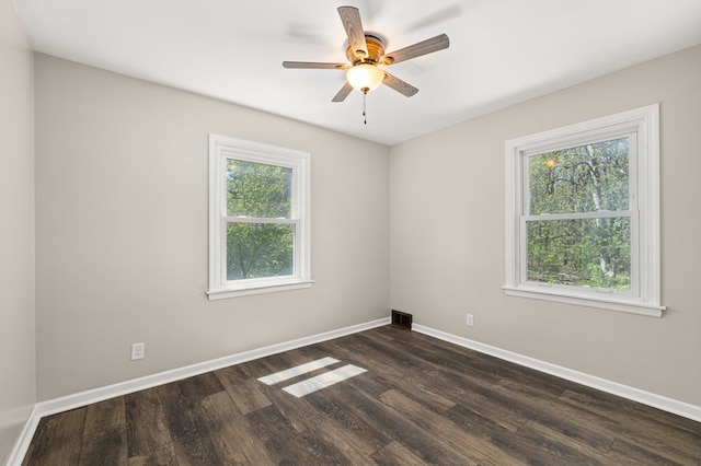 unfurnished room featuring dark wood-style flooring, visible vents, a ceiling fan, and baseboards
