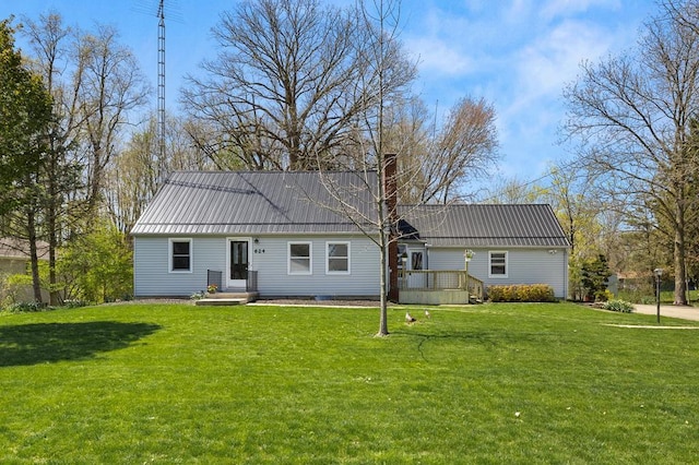 rear view of house featuring a chimney, a deck, metal roof, and a yard