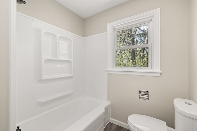 full bath featuring toilet, baseboards, and  shower combination