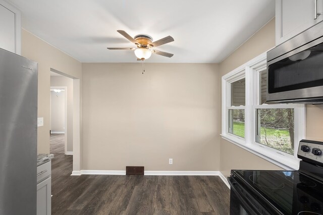 kitchen with stainless steel microwave, dark wood-style flooring, range with electric cooktop, a ceiling fan, and baseboards