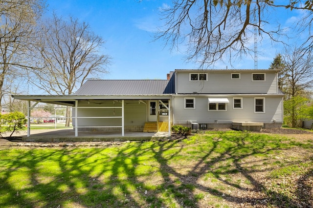 back of house with a chimney, entry steps, metal roof, and a lawn