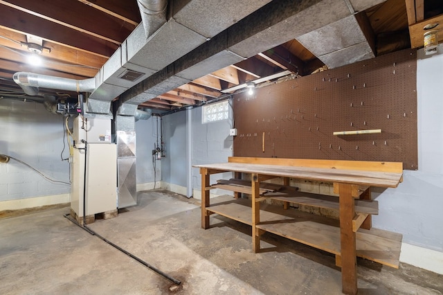 below grade area with a workshop area, heating unit, visible vents, and baseboards