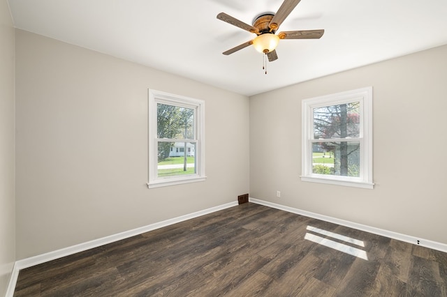 spare room featuring baseboards, ceiling fan, and dark wood-type flooring