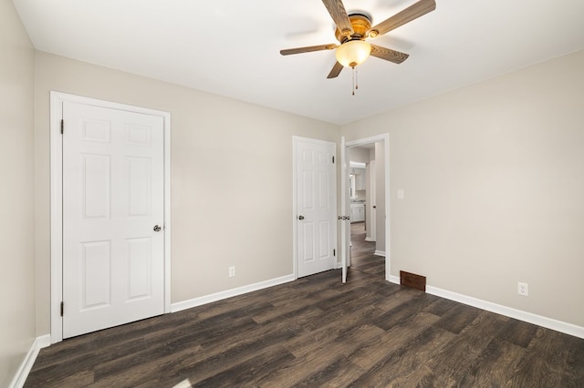 unfurnished bedroom featuring dark wood-type flooring, a ceiling fan, visible vents, and baseboards