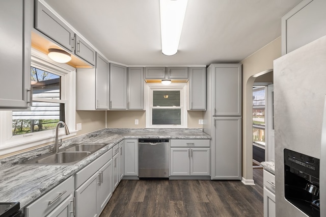 kitchen featuring dark wood finished floors, stainless steel appliances, arched walkways, and a sink