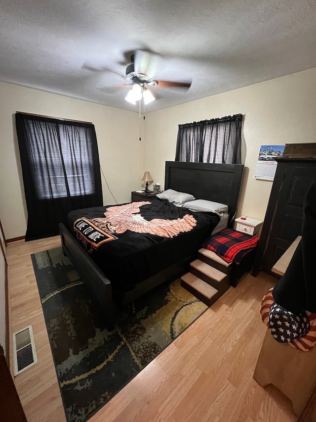 bedroom featuring a textured ceiling, light hardwood / wood-style floors, and ceiling fan