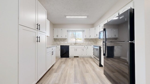 kitchen featuring decorative backsplash, light wood-style flooring, white cabinetry, a sink, and black appliances