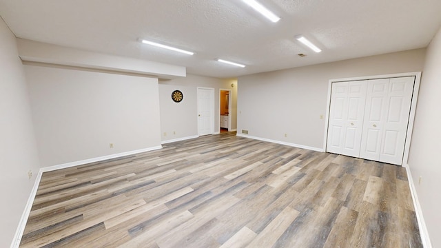 unfurnished room featuring baseboards, a textured ceiling, and light wood finished floors