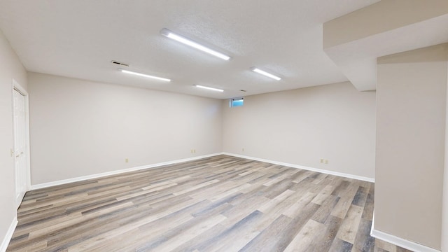 unfurnished room featuring baseboards, visible vents, light wood-style flooring, and a textured ceiling