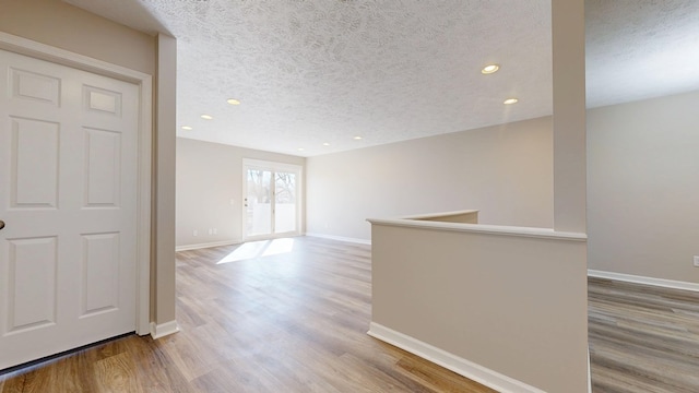 spare room with baseboards, wood finished floors, and a textured ceiling
