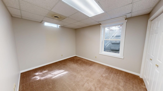 below grade area featuring carpet floors, baseboards, visible vents, and a paneled ceiling