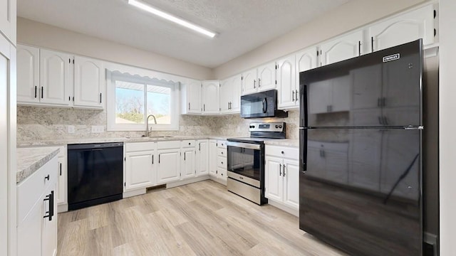 kitchen featuring a sink, white cabinets, black appliances, and light wood-style floors