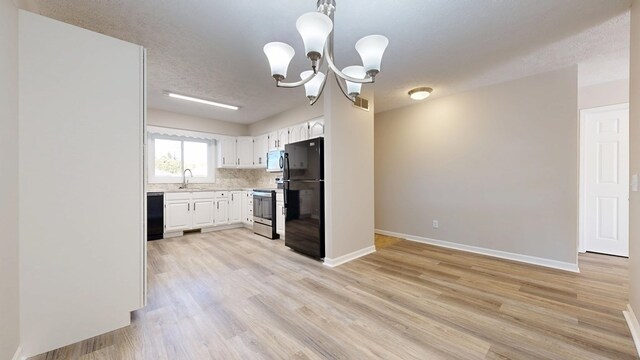 kitchen with light countertops, stainless steel appliances, a sink, light wood finished floors, and a notable chandelier