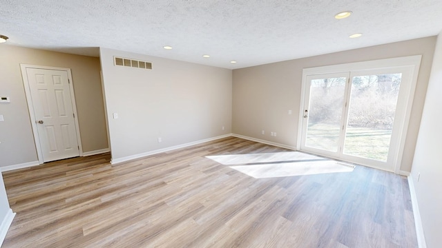 empty room featuring a textured ceiling, visible vents, baseboards, recessed lighting, and light wood-type flooring
