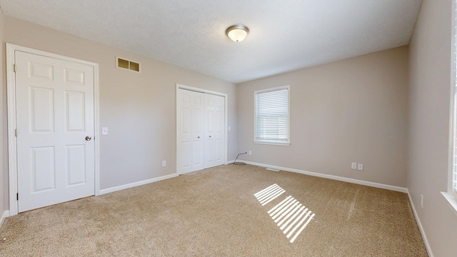unfurnished bedroom with a closet, a textured ceiling, baseboards, and visible vents