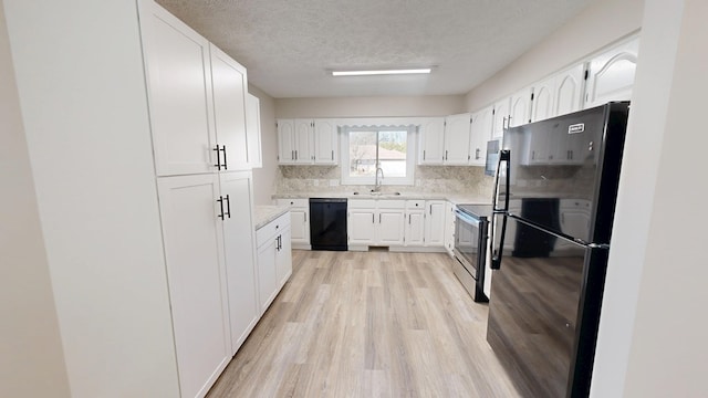 kitchen featuring white cabinetry, black appliances, light wood-style floors, and a sink