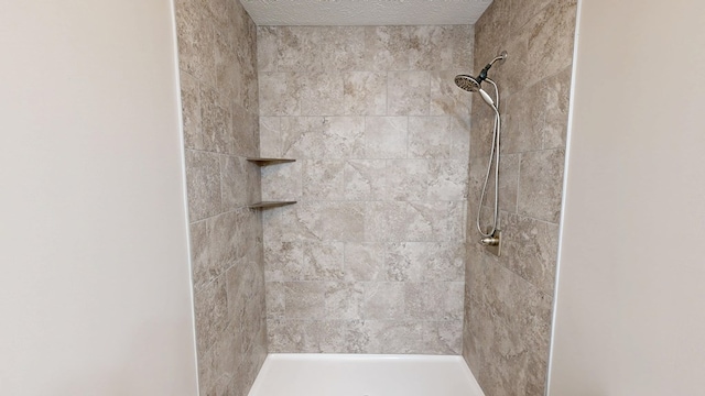 bathroom featuring tiled shower and a textured ceiling
