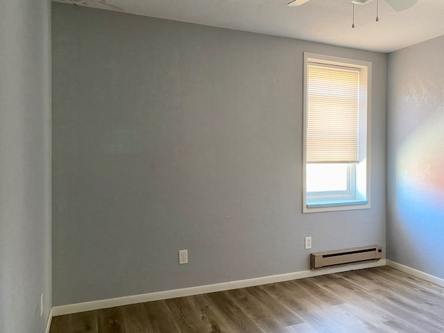 unfurnished room featuring ceiling fan, light hardwood / wood-style floors, and baseboard heating