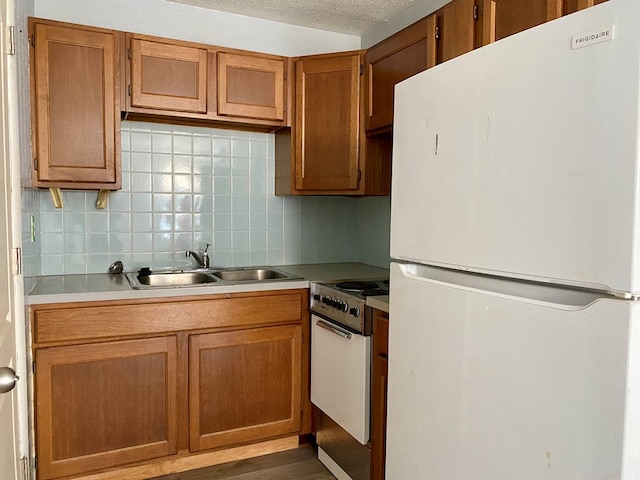 kitchen featuring sink, dark hardwood / wood-style floors, a textured ceiling, white appliances, and decorative backsplash