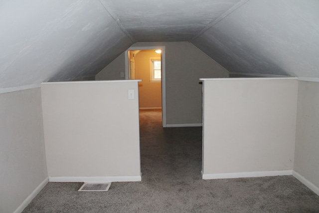 bonus room with vaulted ceiling and dark colored carpet