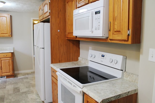 kitchen featuring a textured ceiling and white appliances