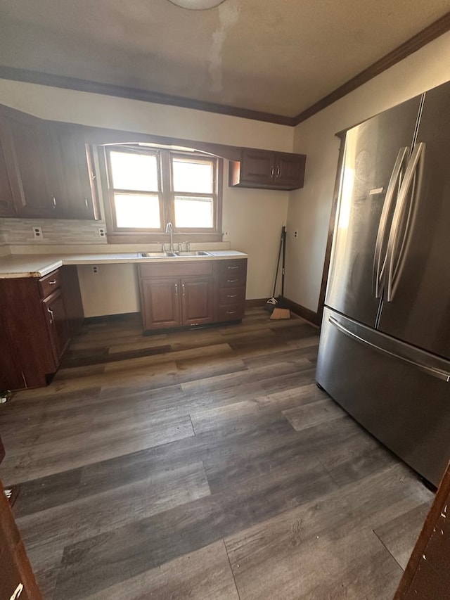 kitchen with dark wood finished floors, light countertops, ornamental molding, freestanding refrigerator, and a sink