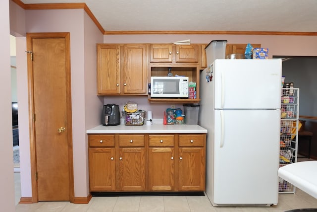 kitchen with white appliances, light tile patterned floors, light countertops, crown molding, and brown cabinets