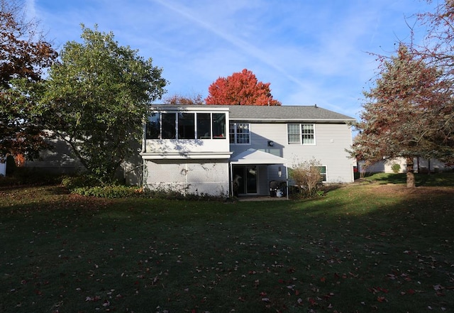 rear view of property with a lawn and a sunroom