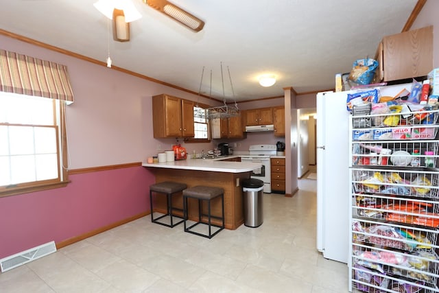 kitchen featuring white appliances, visible vents, ornamental molding, under cabinet range hood, and brown cabinets