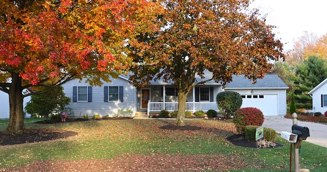 view of property hidden behind natural elements with a porch, concrete driveway, a garage, and a front lawn