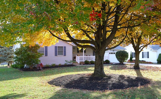 obstructed view of property with covered porch, an attached garage, and a front yard