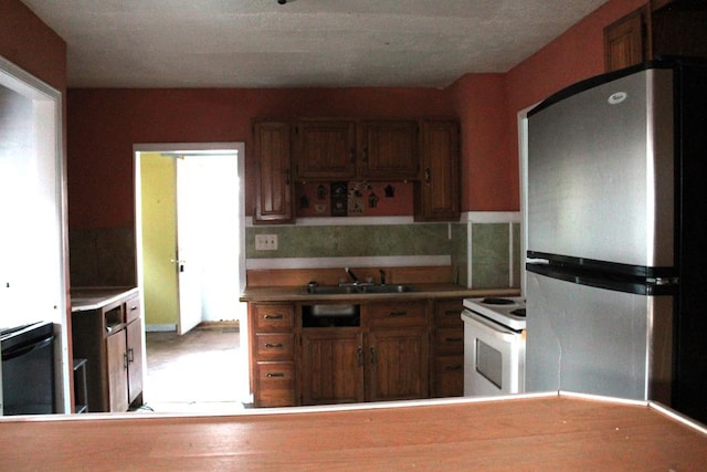 kitchen featuring backsplash, sink, electric range, black dishwasher, and stainless steel refrigerator